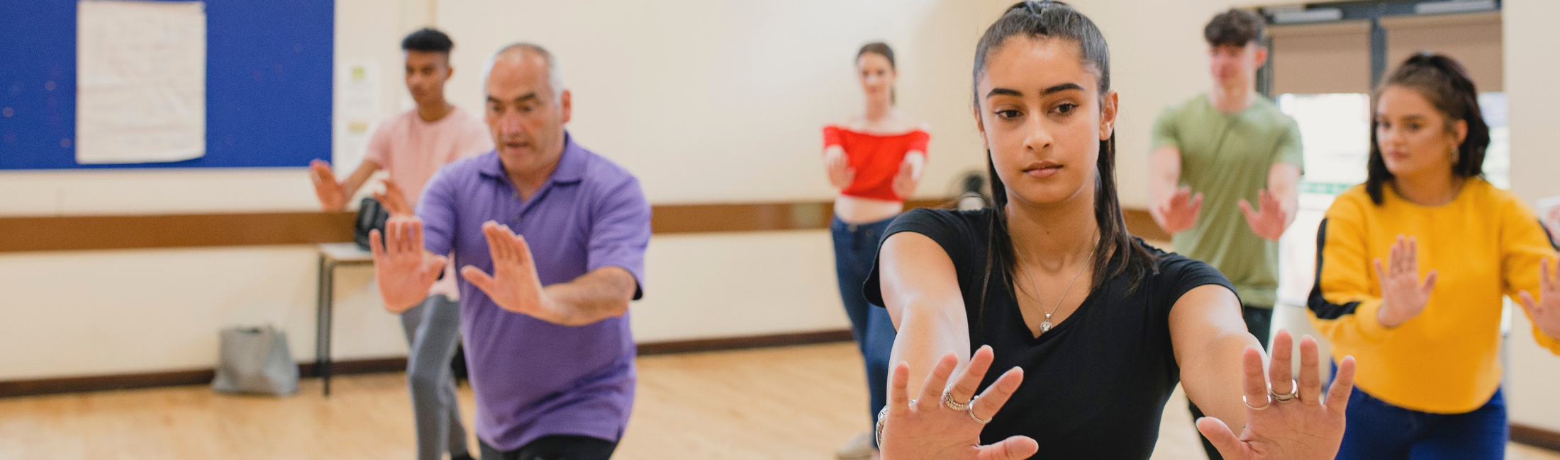 Six people in a room with arms pushing outward, practicing tai chi