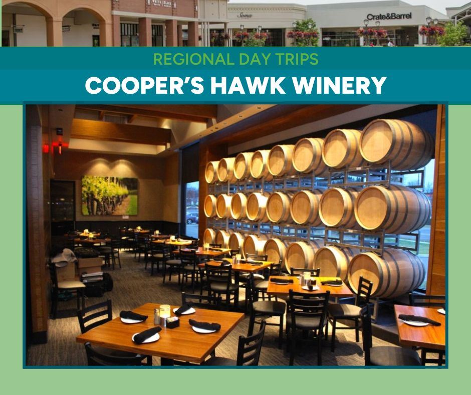 A photo of an elegant dining room with wine barrels stacked against a wall with set dining tables.