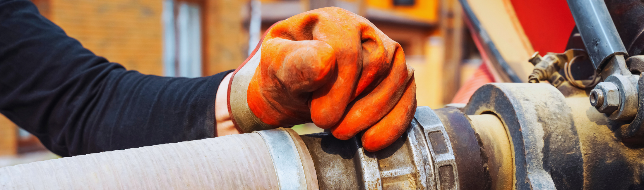 Gloved hand holds a hose that is pumping out a septic system.